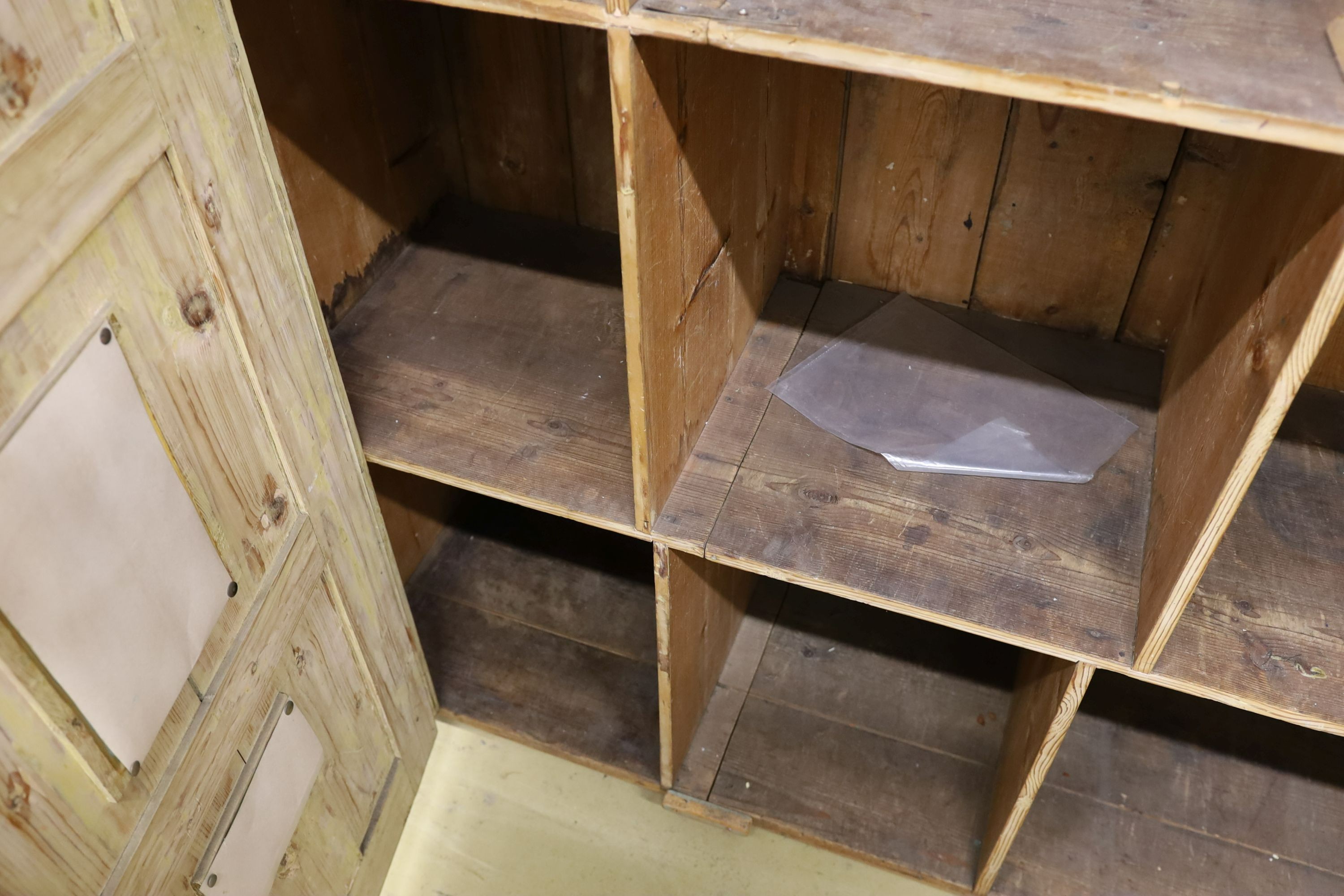 A 19th century stripped pine hall cupboard modelled as a dolls house the two door nine window facade enclosing a compartmented interior, width 182cm, depth 46cm, height 192cm